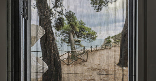 A view from inside a motorhome looking out through a screened doorway, showing trees and a body of water beyond.